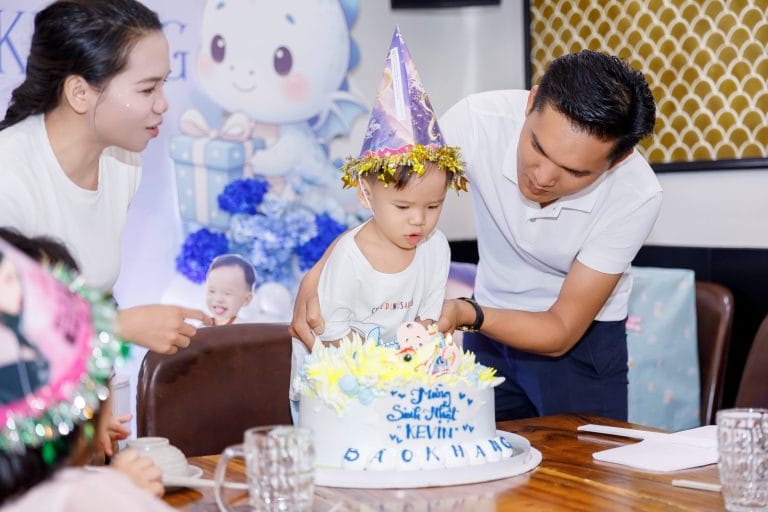Ba đỡ bé thổi nến bánh sinh nhật trong tiệc thôi nôi tại nhà hàng ở Tân An, Long An