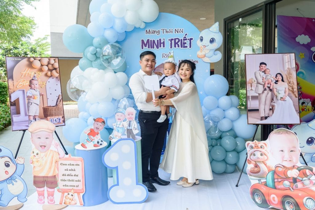 Ba mẹ bế bé chụp ảnh trước backdrop tiệc thôi nôi, NHƯ Photo chụp tận nơi tại Long An