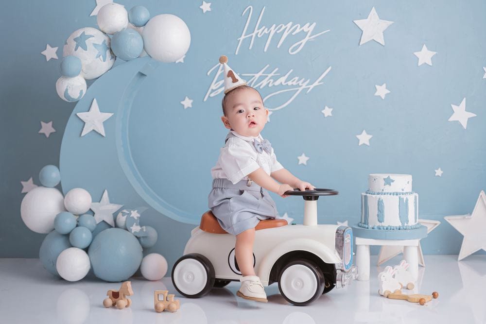 Chụp ảnh thôi nôi bé trai cưỡi xe trên nền sinh nhật xanh tại studio NHƯ Photo Tân An, Long An